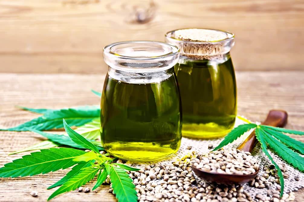 dos frascos de cristal con aceite y semillas de canamo y hojas cannabis sativa