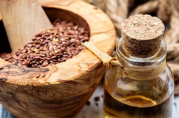 cuenco de madera con semillas de lino y una aceitera con aceite de lino
